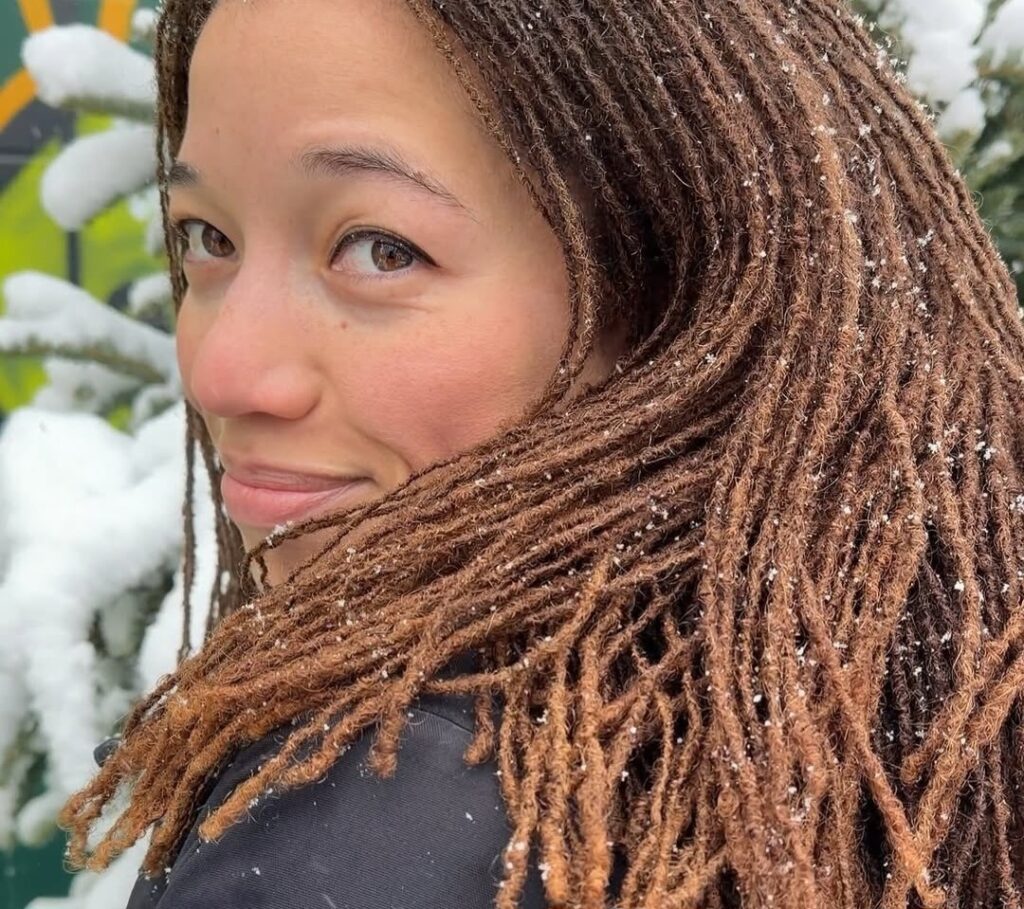 Woman with medium-length brown locs styled naturally, showing healthy texture and even sizing.