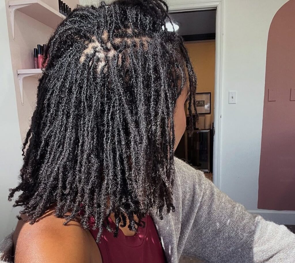 Woman showing the neat roots of her locs