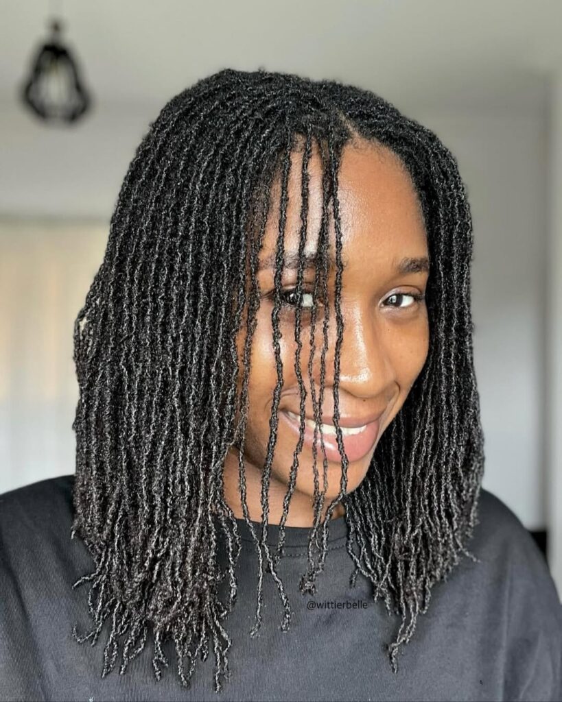 Close up shot of a woman on locs with few strands covering a  small part of her face