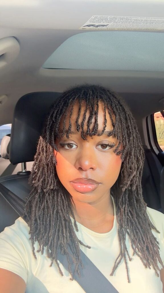 Woman on sisterlocks with bangs sitting in a car
