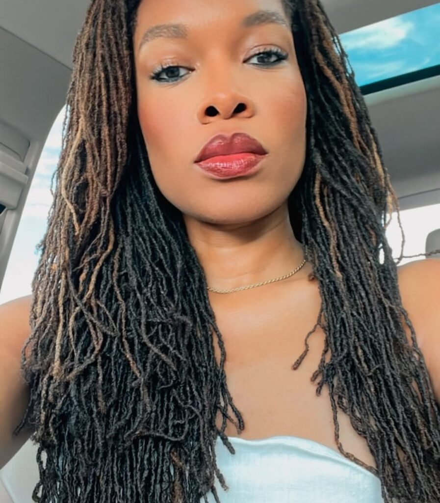 Close-up selfie of a woman with long locs sitting in a car, showing detailed loc texture and length in natural lighting.