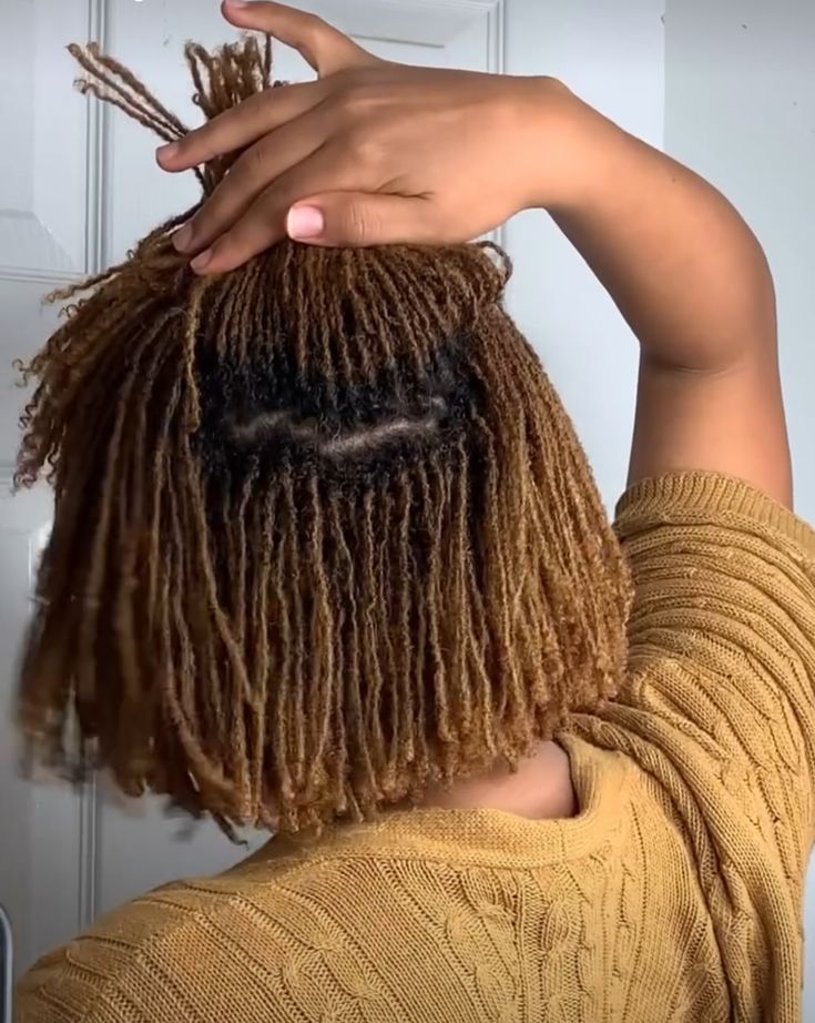 Back view of a woman on microlocs, raising one section of her locs.