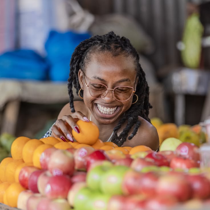 A lady in locs holding fruits