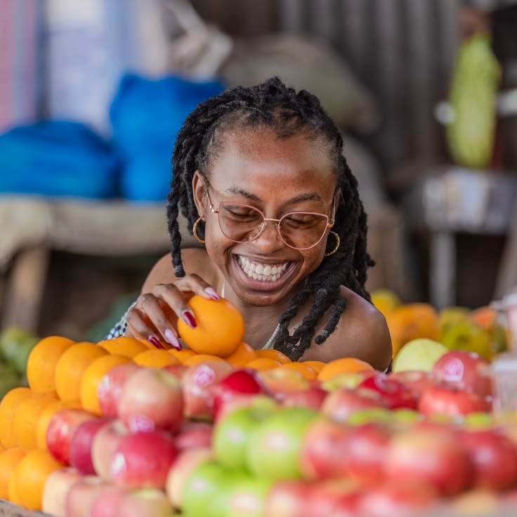 A lady in locs holding fruits